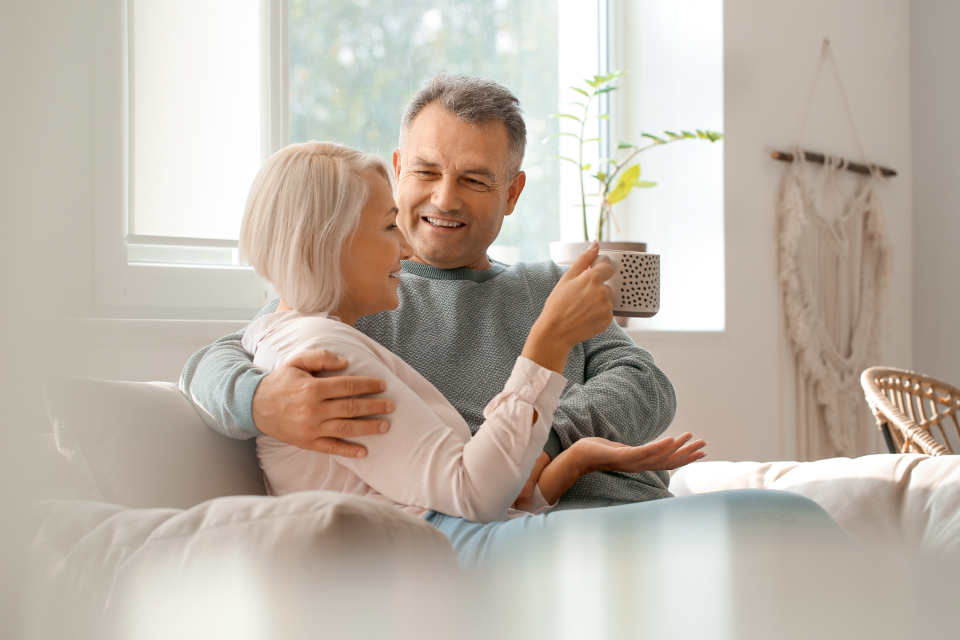 Un couple rit ensemble sur un canapé, une tasse à la main